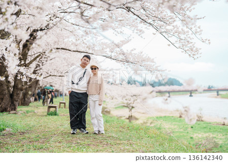 Couple tourist sightseeing Sakura Cherry Blossom in Spring. Happy traveler travel near Hinokinai River riverbank in Kakunodate town, Semboku District, Akita Prefecture, Japan. Landmark and Vacation Couple tourist sightseeing Sakura Cherry Blossom in Spring. Happy traveler travel near Hinokinai River riverbank in Kakunodate town, Semboku District, Akita Prefecture, Japan. Landmark and Vacation 136142340