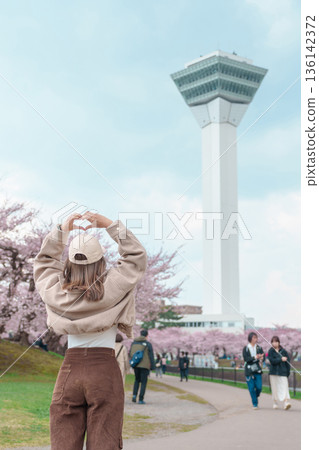 Woman tourist sightseeing Goryokaku Tower park with Sakura Cherry Blossom in Spring, happy traveler travel in Hakodate city, Hokkaido, Japan. famous Landmark, Japan Travel and Vacation destination 136142372