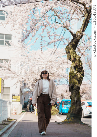 Woman tourist sightseeing Goryokaku Tower park with Sakura Cherry Blossom in Spring, happy traveler travel in Hakodate city, Hokkaido, Japan. famous Landmark, Japan Travel and Vacation destination 136142373