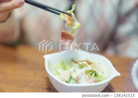 Woman eating Caesar salad with Crisp romaine lettuce tossed and ham 136142513