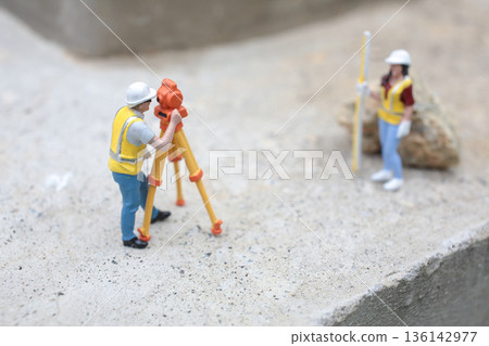 Miniature Surveyors Working With Tripod Equipment On Concrete Surface Miniature Surveyors Working With Tripod Equipment On Concrete Surface 136142977