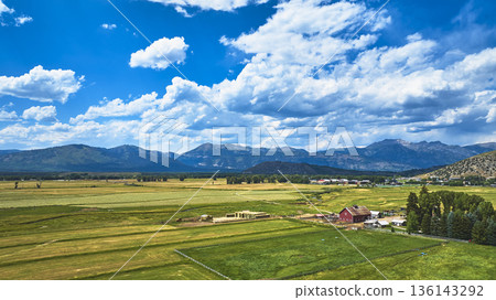 Aerial Wyoming Farmland Red Barn and Mountain Range Under Vibrant Sky Aerial Wyoming Farmland Red Barn and Mountain Range Under Vibrant Sky 136143292