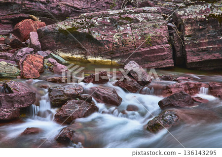 Red Rock Point Cascades Over Colorful River Rocks in Glacier National Park Montana 136143295