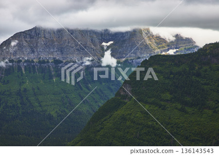 Moody Cloud Covered Mountain Range and Lush Forest in Glacier National Park Moody Cloud Covered Mountain Range and Lush Forest in Glacier National Park 136143543