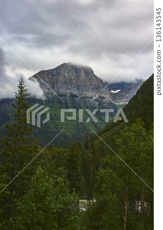Clouds Rolling Over Rugged Mountain Peak and Dense Forest in Lush Green Wilderness Clouds Rolling Over Rugged Mountain Peak and Dense Forest in Lush Green Wilderness 136143545