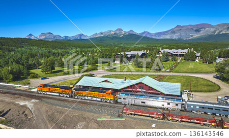 Aerial East Glacier Train Station Colorful Locomotive and Majestic Mountain Landscape 136143546