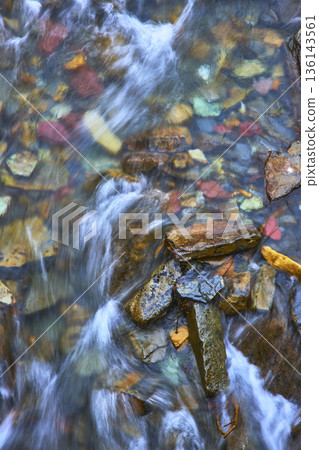 Colorful River Stones and Flowing Water Cascade in Pristine Nature Scene 136143561