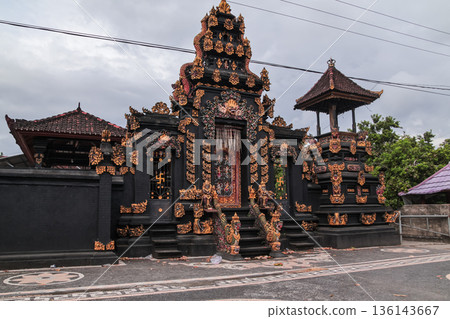 Traditional Balinese temple gate with gold ornaments under cloudy sky for travel concept Traditional Balinese temple gate with gold ornaments under cloudy sky for travel concept 136143667