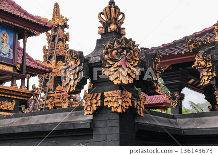 Balinese temple stone carving with gold leaf details under natural light for travel concept 136143673