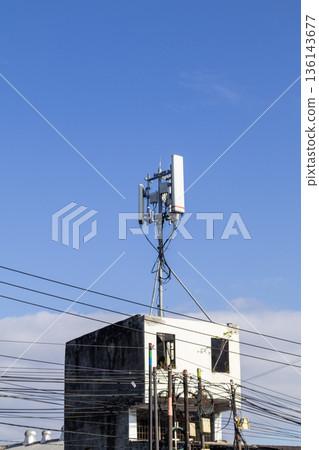 Telecommunication tower mounted on building roof against clear blue sky for mobile network connectivity Telecommunication tower mounted on building roof against clear blue sky for mobile network connectivity 136143677