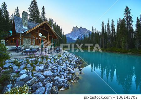Emerald Lake Lodge Reflected in Water at Sunrise Surrounded by Forest and Rocky Shore 136143702