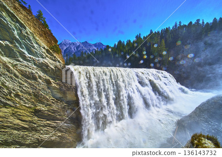 Wapta Falls Waterfall with Rocky Cliff and Dense Pine Forest Under Blue Sky 136143732