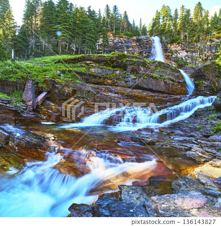 Waterfall Flowing Over Rocky Ledges With Evergreen Forest And Clear Water Waterfall Flowing Over Rocky Ledges With Evergreen Forest And Clear Water 136143827