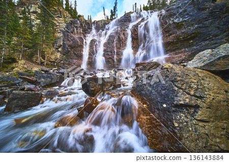 Tangle Falls Waterfall Flowing Over Rocky Cliff with Evergreen Forest in Jasper 136143884