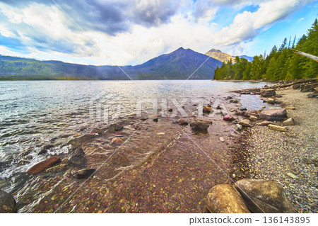 Lake McDonald Rocky Shoreline Clear Water and Distant Mountain Scenery Lake McDonald Rocky Shoreline Clear Water and Distant Mountain Scenery 136143895