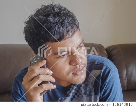 man using mobile phone on sofa at home 136143913