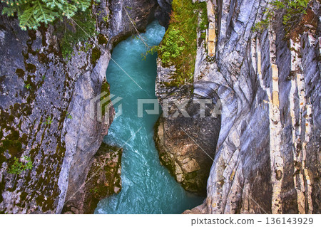 Top Down Turquoise River Flowing Through Rugged Canyon Walls and Lush Vegetation 136143929