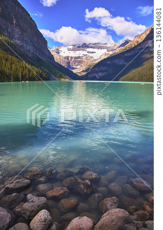 Turquoise Glacier Lake with Rocky Shore and Snow Capped Mountain Reflections 136144081