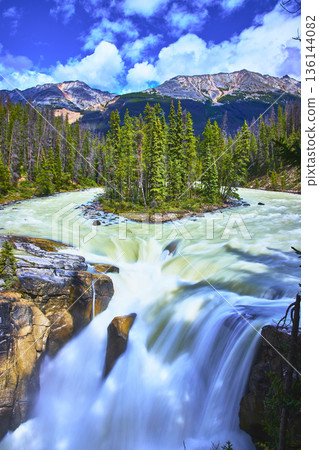 Sunwapta Falls Rushing Waterfall and Forested Island with Majestic Mountain Backdrop 136144082