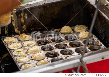 Cooking Asian street food snacks in round metal mold pan for culinary concept Cooking Asian street food snacks in round metal mold pan for culinary concept 136144227