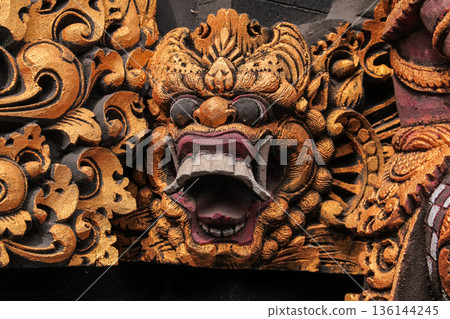 Traditional Balinese stone carving with gold leaf finish on temple wall for cultural heritage concept Traditional Balinese stone carving with gold leaf finish on temple wall for cultural heritage concept 136144245