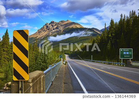 Highway Through Pine Forest With Mountain And Cloud In Banff Canada Highway Through Pine Forest With Mountain And Cloud In Banff Canada 136144369