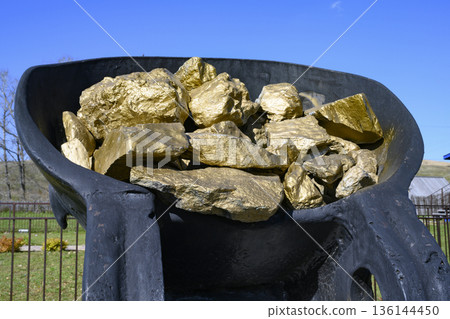 Monument to gold miners in the form of huge pieces of gold in a metal bucket 136144450