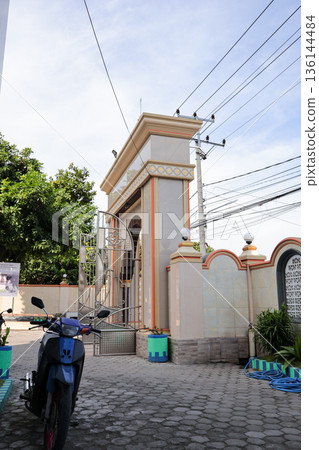 Entrance Gate to Building Under Natural Light with Architectural Detail and Clear Sky Backdrop for Travel and Cultural Heritage Concepts Entrance Gate to Building Under Natural Light with Architectural Detail and Clear Sky Backdrop for Travel and Cultural Heritage Concepts 136144484