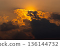 Golden sun behind dark clouds with warm light in the sky 136144732