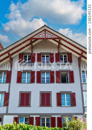 Stunning Swiss Architecture A Detailed Building Front with Vibrant Red Shutters on a Sunny Day Stunning Swiss Architecture A Detailed Building Front with Vibrant Red Shutters on a Sunny Day 136145131