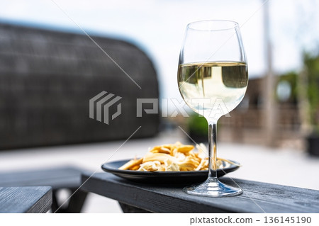 Elegant Wine Glass and Appetizers on a Wooden Table for Relaxing Outdoor Moments 136145190