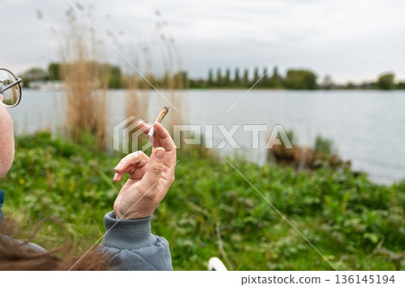 Contemplative Moment Woman Smoking by the Serene Lake, Enjoying Nature s Tranquility Contemplative Moment Woman Smoking by the Serene Lake, Enjoying Nature s Tranquility 136145194