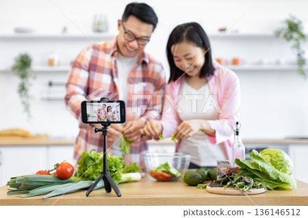 An Asian couple is preparing a healthy salad in their kitchen while recording a video for their online audience An Asian couple is preparing a healthy salad in their kitchen while recording a video for their online audience 136146512