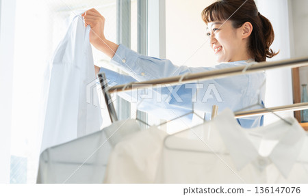 A woman hanging up the laundry A woman hanging up the laundry 136147076
