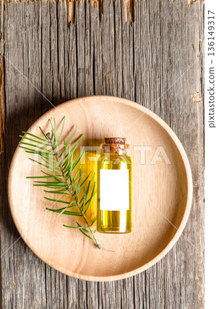 Top view composition of essential fir oil bottle with green leaves on wooden plate on rustic wood 136149317