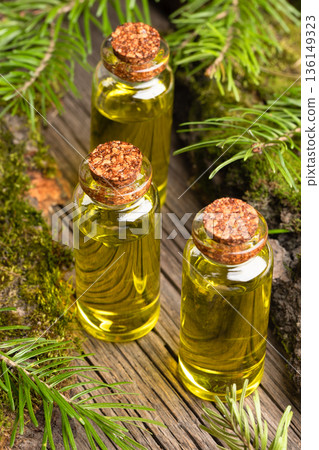 Set of essential fir oil bottles with cork stoppers on old wood surrounded by pine branches. Set of essential fir oil bottles with cork stoppers on old wood surrounded by pine branches. 136149323