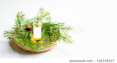 Essential fir oil bottle surrounded by branches on wooden plate Banner with copy space 136149327