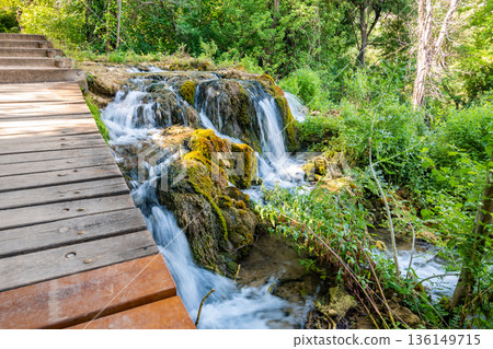 Waterfalls at Skradinski Buk, national nature park Krka, Croatia. Flowing water in beautiful nature, green plants and trees. Sunny summer day. 136149715