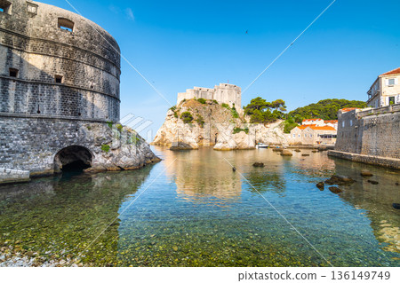 View of small water bay near old city of Dubrovnik. Ancient fort Lovrijenac near small harbor with boats. Sunny day. View of small water bay near old city of Dubrovnik. Ancient fort Lovrijenac near small harbor with boats. Sunny day. 136149749