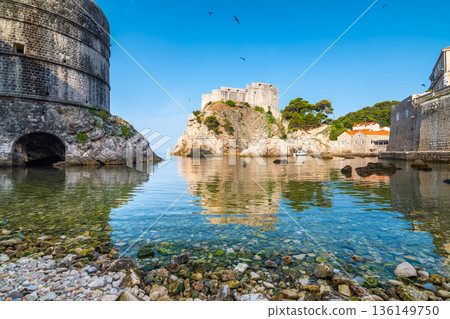 View of small water bay near old city of Dubrovnik. Ancient fort Lovrijenac near small harbor with boats. Sunny day. View of small water bay near old city of Dubrovnik. Ancient fort Lovrijenac near small harbor with boats. Sunny day. 136149750