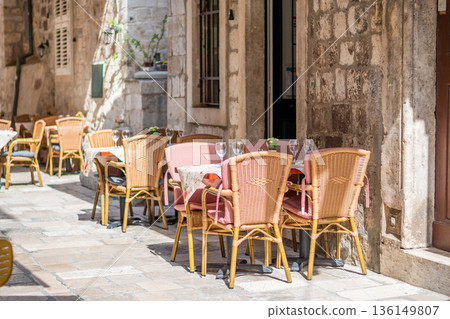 Table and chairs at the restaurant in narrow street are prepared for guests and tourist. Old city of Dubrovnik, Croatia. 136149807
