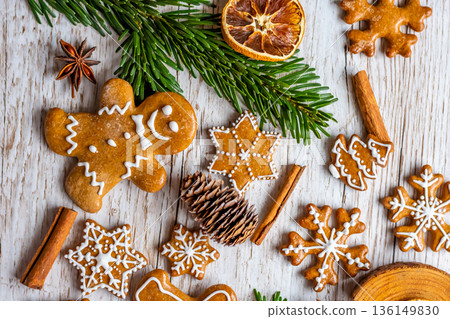 Christmas gingerbread and sweets are placed on wooden desk. Cookies and sweet food in shape of stars and snow flakes. Winter theme, rustic style. Pine trees on the side. Candy stick and other spice. Christmas gingerbread and sweets are placed on wooden desk. Cookies and sweet food in shape of stars and snow flakes. Winter theme, rustic style. Pine trees on the side. Candy stick and other spice. 136149830