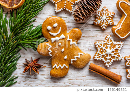 Christmas gingerbread and sweets are placed on wooden desk. Cookies and sweet food in shape of stars and snow flakes. Winter theme, rustic style. Pine trees on the side. Candy stick and other spice. Christmas gingerbread and sweets are placed on wooden desk. Cookies and sweet food in shape of stars and snow flakes. Winter theme, rustic style. Pine trees on the side. Candy stick and other spice. 136149831