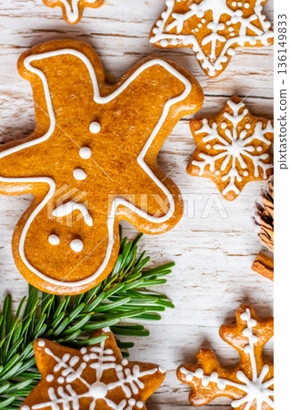Christmas gingerbread and sweets are placed on wooden desk. Cookies and sweet food in shape of stars and snow flakes. Winter theme, rustic style. Pine trees on the side. Candy stick and other spice. Christmas gingerbread and sweets are placed on wooden desk. Cookies and sweet food in shape of stars and snow flakes. Winter theme, rustic style. Pine trees on the side. Candy stick and other spice. 136149833