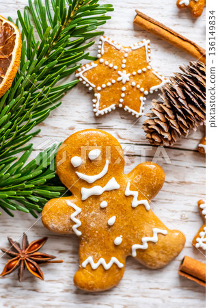 Christmas gingerbread and sweets are placed on wooden desk. Cookies and sweet food in shape of stars and snow flakes. Winter theme, rustic style. Pine trees on the side. Candy stick and other spice. 136149834
