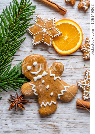 Christmas gingerbread and sweets are placed on wooden desk. Cookies and sweet food in shape of stars and snow flakes. Winter theme, rustic style. Pine trees on the side. Candy stick and other spice. 136149868
