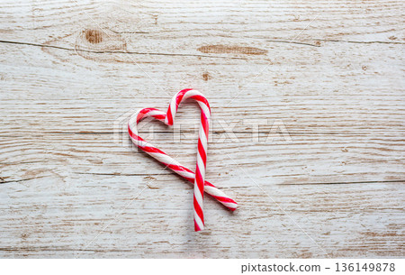 Candy cane christmas sweet red and white striped food in shape of heart. Placed on wooden desk. Winter and christmas theme. Candy cane christmas sweet red and white striped food in shape of heart. Placed on wooden desk. Winter and christmas theme. 136149878