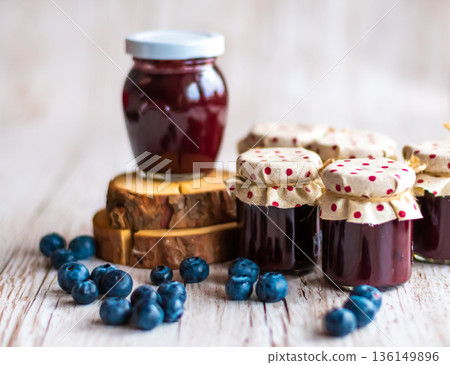 Blueberry jam placed in small glasses on wooden desk. Fresh blueberries around. Homemade marmalade, concept of healthy cooking. 136149896