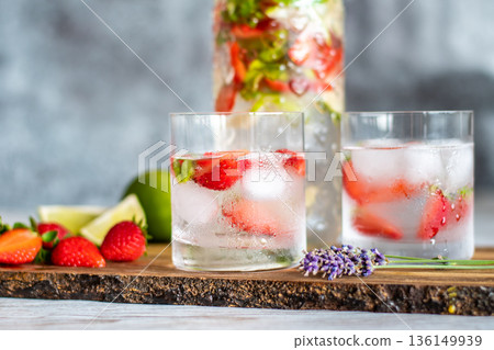 Fresh drink with strawberry and lime placed on wooden desk. Glasses with lemonade and ice. Summer drink. 136149939