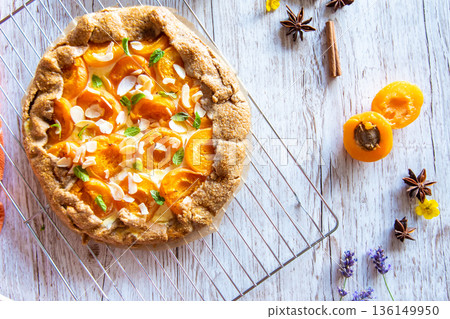 Apricot galette pie cake placed on wooden background with cooking tools on the side Apricot galette pie cake placed on wooden background with cooking tools on the side 136149950